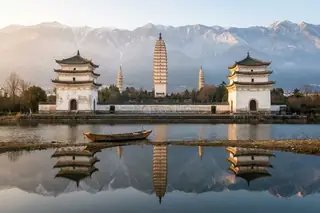 Dali, China — the Three Pagodas of Chongsheng Temple reflected in water with the Cangshan mountains behind
