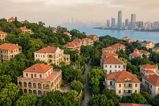 Xiamen, China — Gulangyu island's colonial red-roofed villas amid greenery with the city skyline across the sea